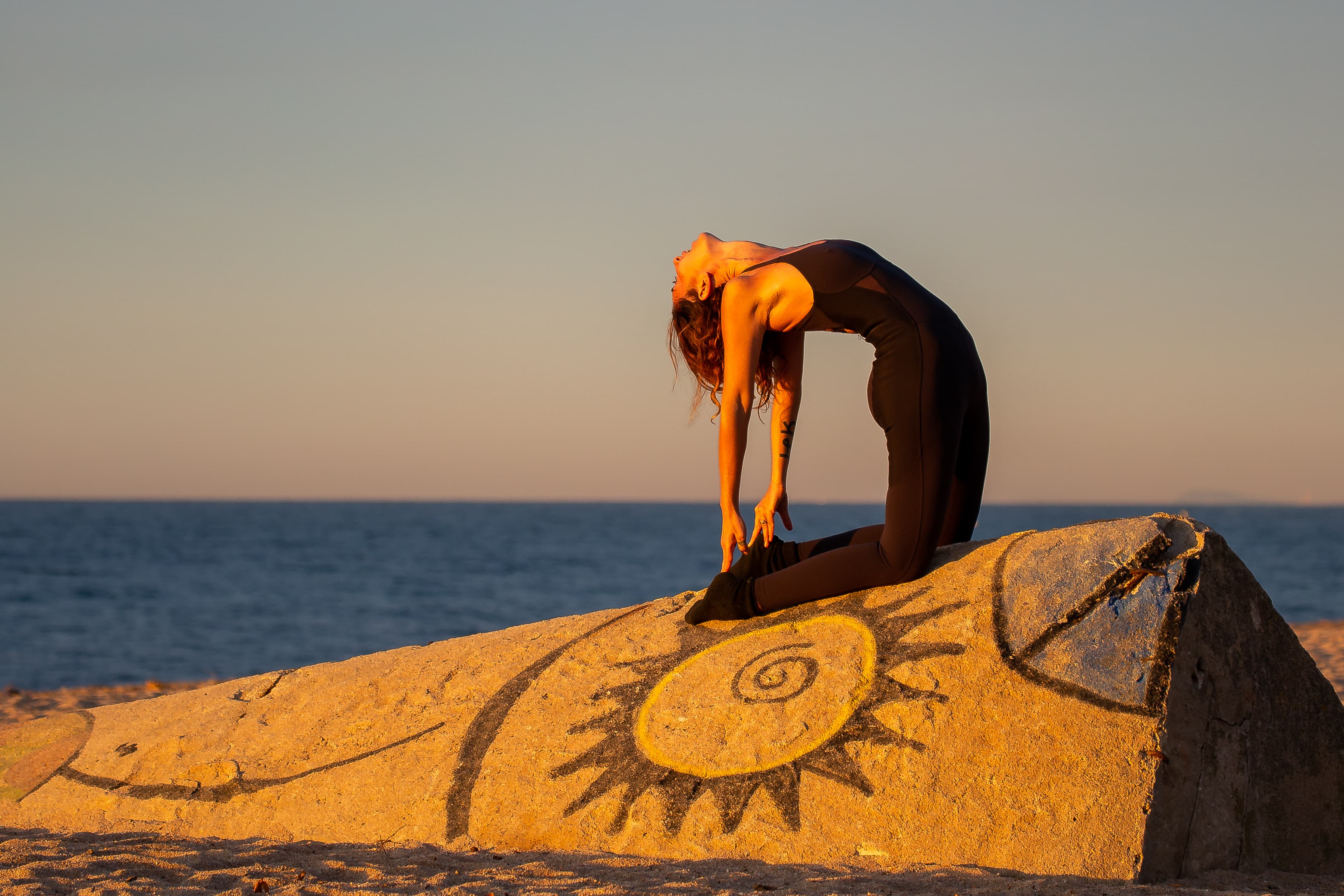 Sarita Shakti en una postura de yoga al atardecer junto al mar.